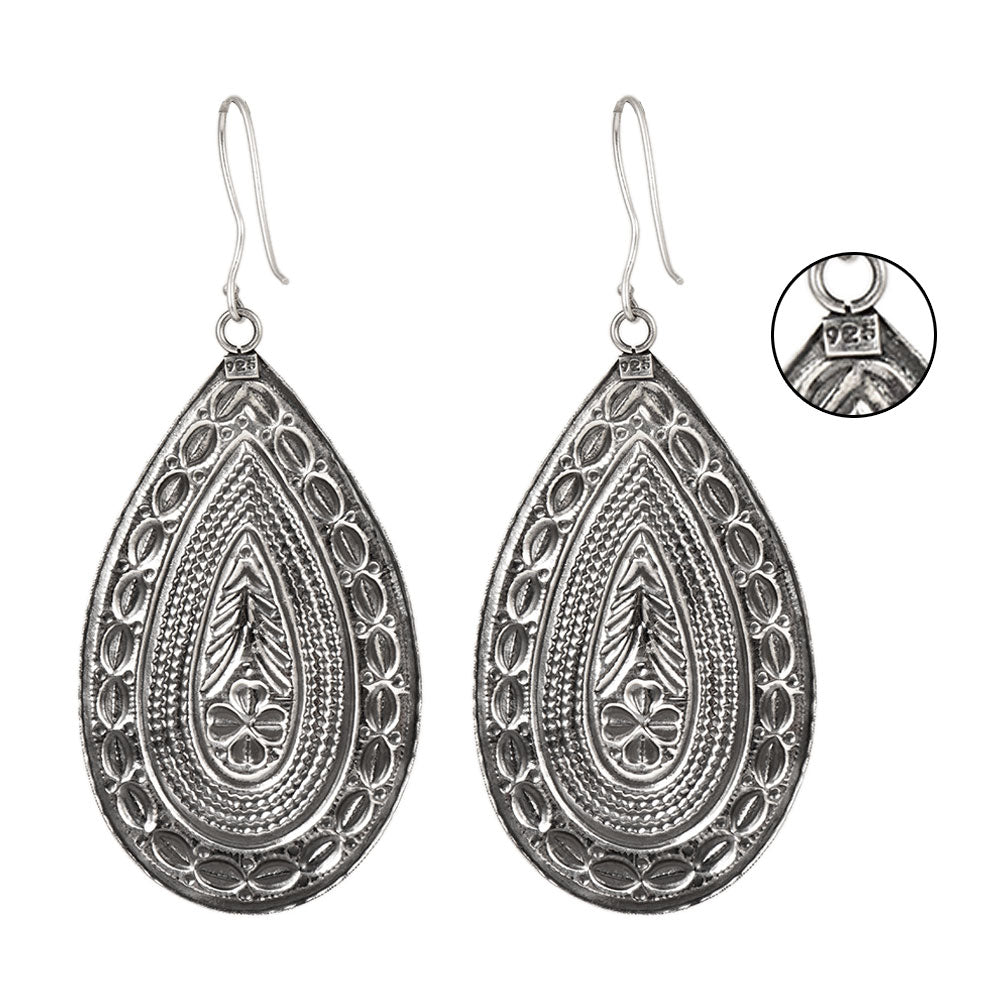 Side angle showing tribala dangle statement dangle earrings with silver tones.