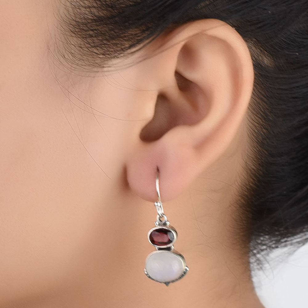 Side angle showing garnet & pearl earrings with silver tones.