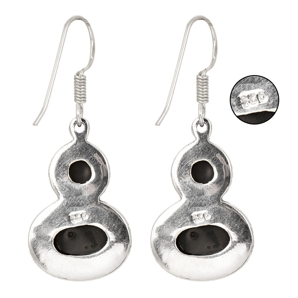 Side angle showing onyx dangle earrings with silver tones.