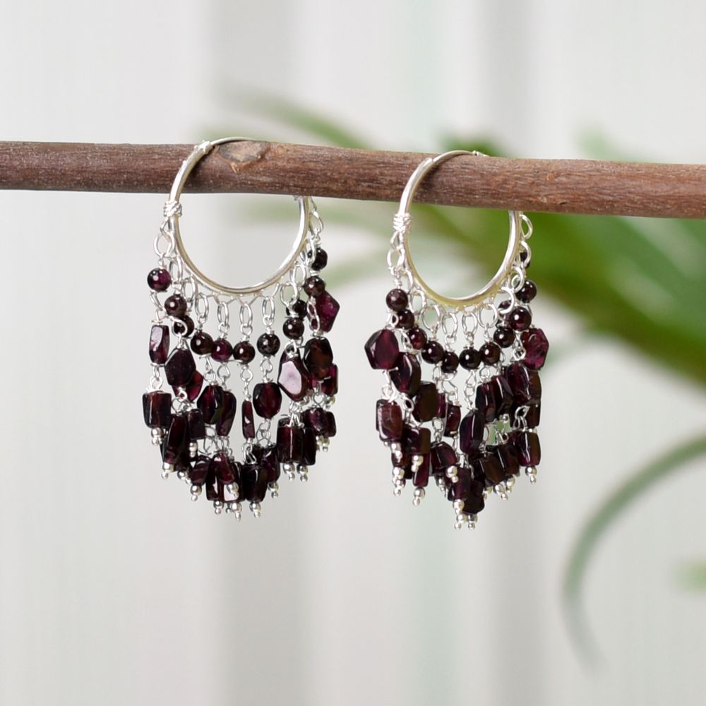 Pair of Garnet Dangle Earrings on a display stand, crafted from 92.5 Sterling Silver.